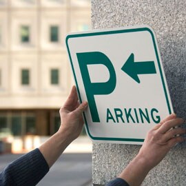 Pracovník připevňující parkovací značku na betonovou zeď